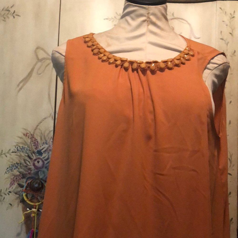 Orange sleeveless top with embellished neck line.